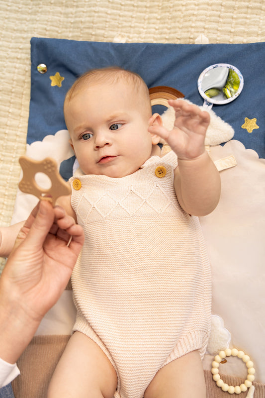 Bébé jouant au parc sur un tapis d’éveil pliable pour développer sa coordination et sa motricité.